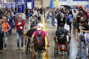 fotografia colorida de um dos corredores da feira Reatech, pessoas com e sem deficiência caminham pelo espaço