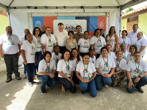 Foto com equipe de colaboradores do Centro Dia perfiladas, todas vestindo camiseta branca com logo do equipamento. No centro da imagem, Secretário Marcos da Costa